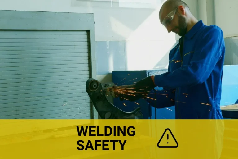 A technician grounding a welder while working on metal in an industrial workshop.