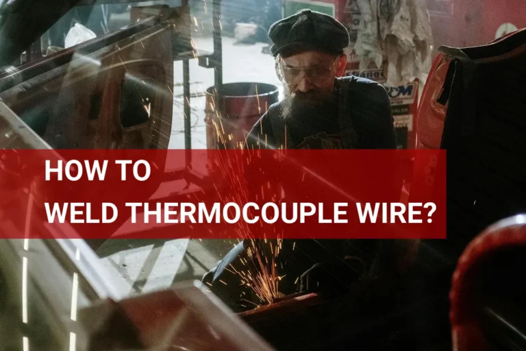 A technician expertly welds thermocouple wire in a bustling auto garage, showcasing precise skills for temperature measurement applications.