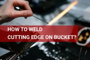 Close-up of a skilled artisan welding a cutting edge onto a bucket with a torch and metalworking tools in a workshop.