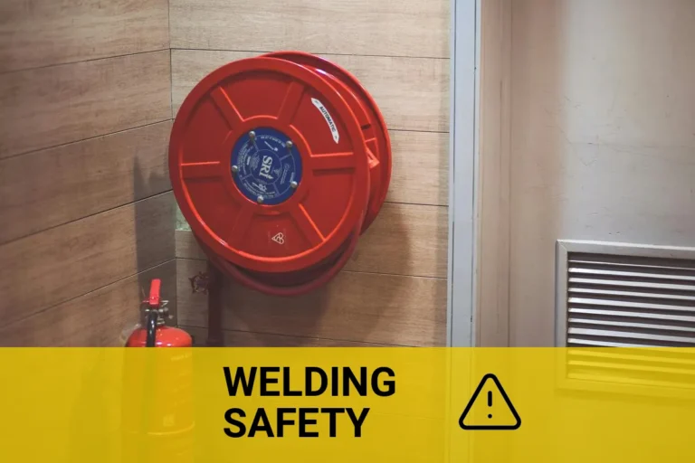 Fire extinguisher for welding safety in a building corner, featuring a red fire hose reel.