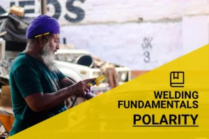Expert welder demonstrating polarity techniques while welding metal in a colorful workshop environment.