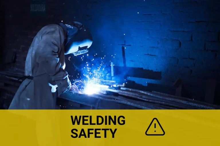 Industrial worker welding zinc plated steel indoors, creating bright blue sparks and smoke.